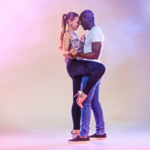 Young couple dances social Caribbean Salsa, studio shot on lilac background. Positive human emotions. The black african and caucasian models