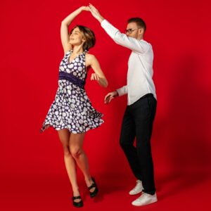 Rock n roll. Old-school fashioned young woman dancing isolated on red studio background. Artist fashion, motion and action concept, youth culture, fashion returning. Young stylish man and woman.